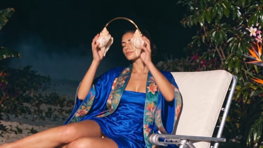 Woman in a blue silk robe wearing a seashell headpiece in a night garden